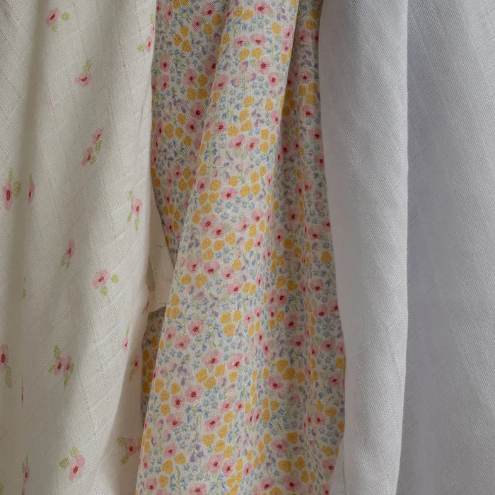 Three types of fabric muslin cloths with floral patterns hanging together.